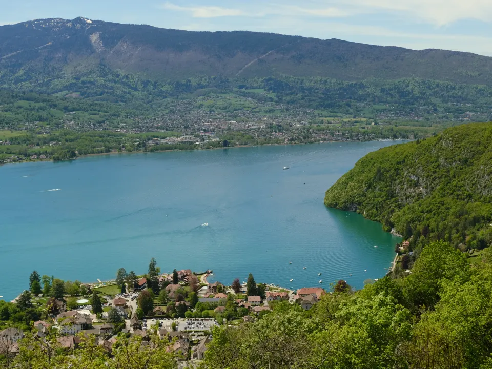 Les eaux turquoise du lac d'Annecy et la baie de Talloires, entourées de montagnes boisées