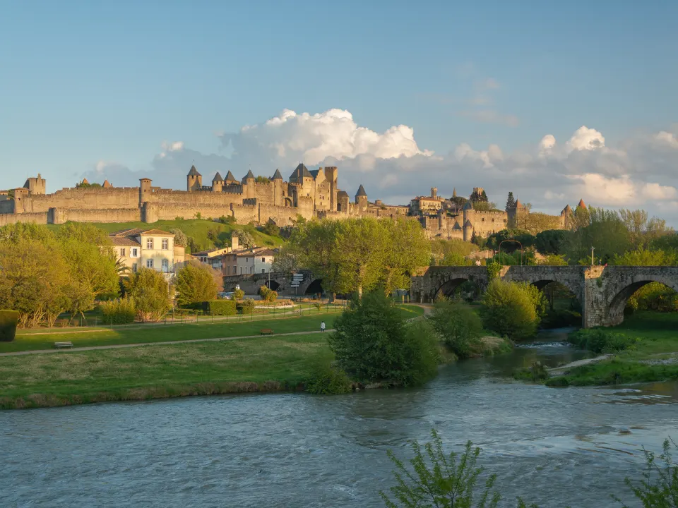 Les remparts de la cité de Carcassonne dominant l'Aude et le Pont-Vieux, dans la lumière du soir