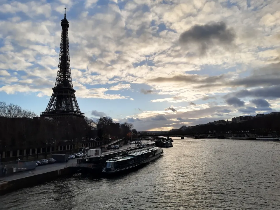 La tour Eiffel se dressant au bord de la Seine à Paris, sous un ciel de nuages au crépuscule